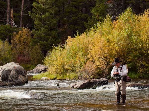 fly fisherman putting a fly on the line in colorado
